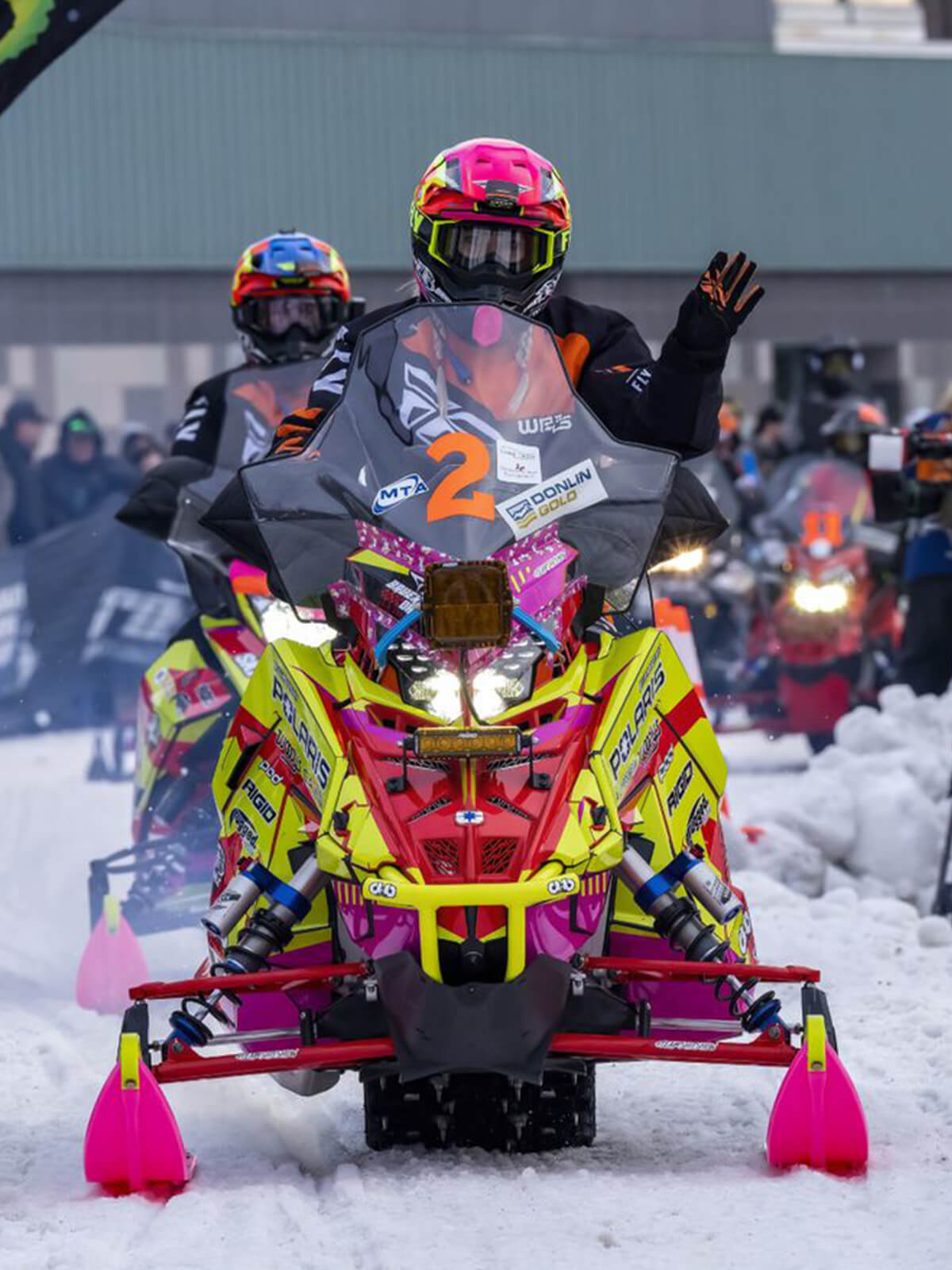 Leah Bauer and Jacob Dahle racing the Iron Dog with pink and yellow Polaris snowmobiles and Pink C&A Pro XPT Skis