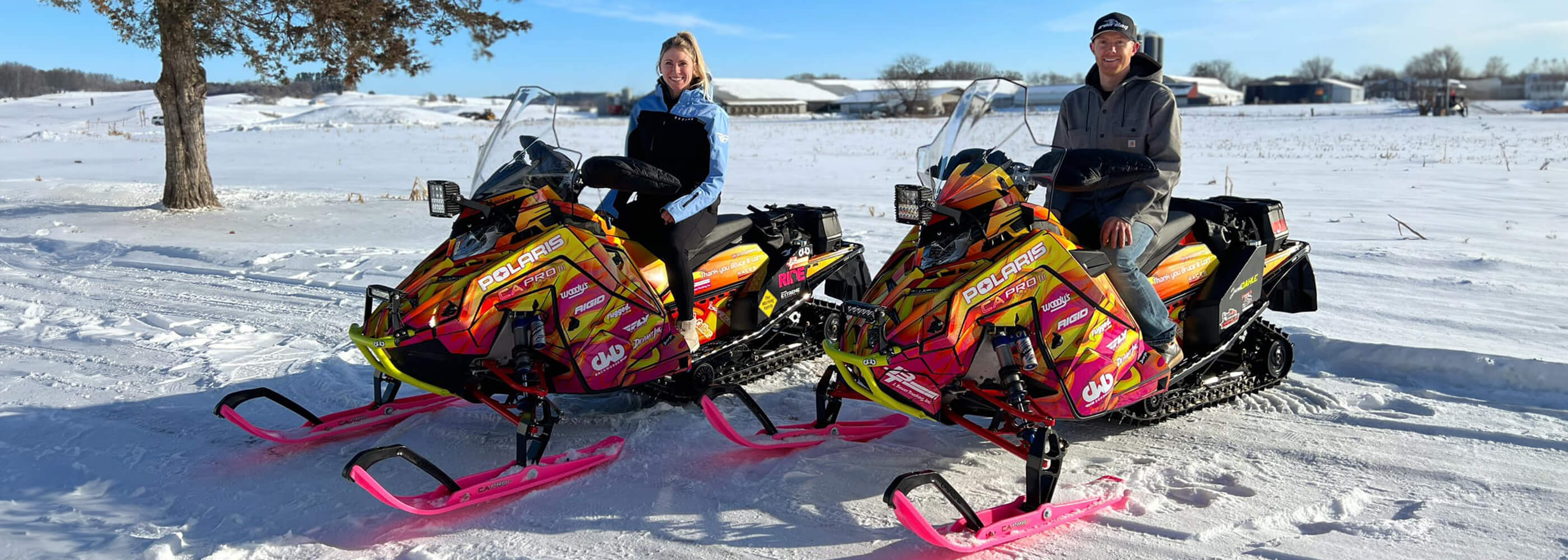 Leah Bauer and Jacob Dahle racing the Iron Dog with pink and yellow Polaris snowmobiles and Pink C&A Pro XPT Skis