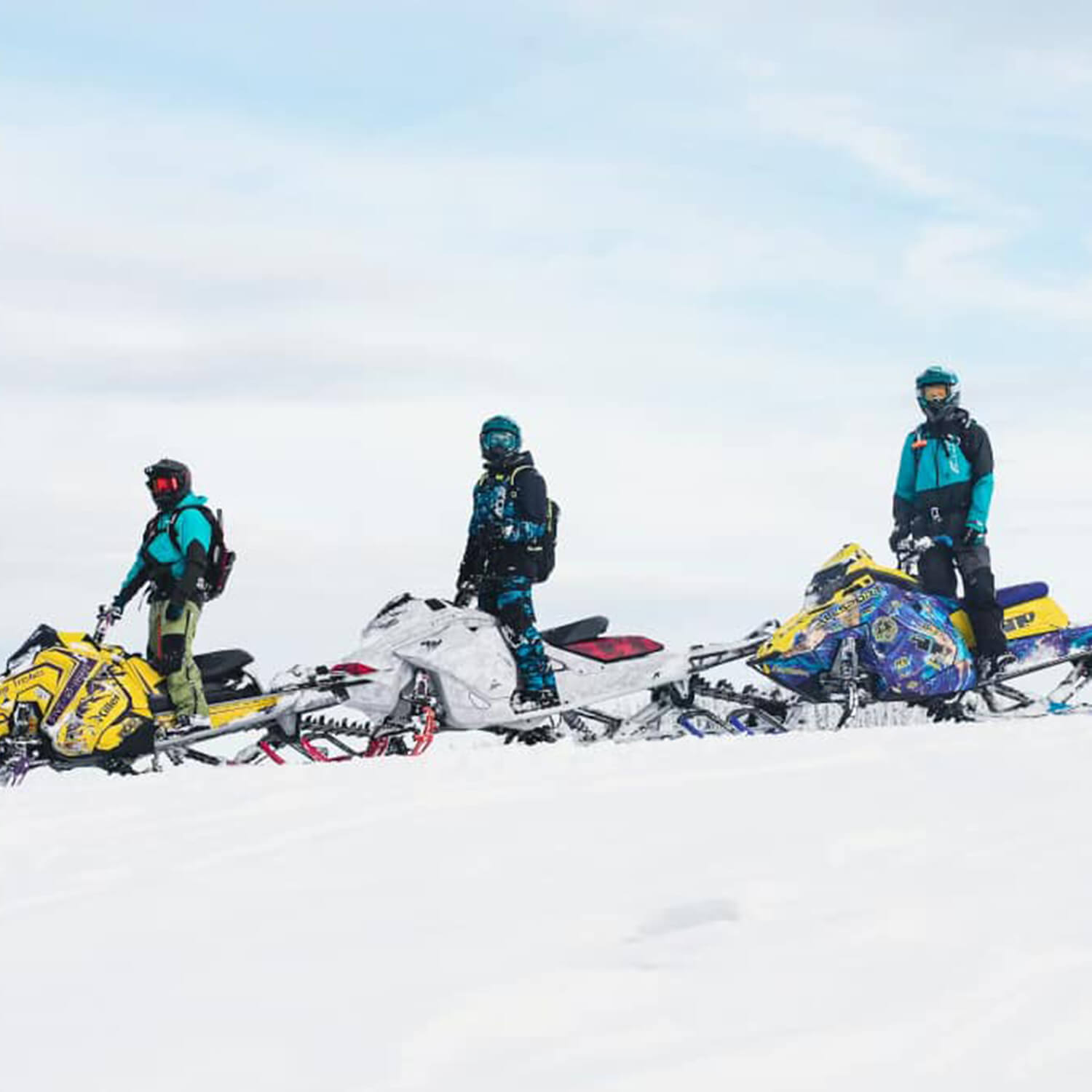 Backcountry snowmobile team Coeur Freshies standing in the snow with snowmobiles