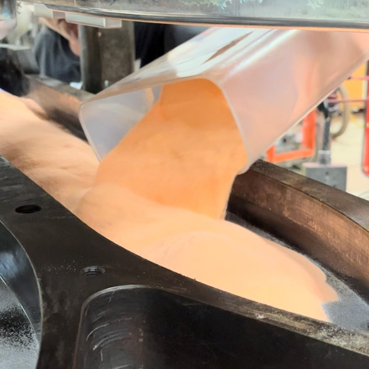 Pouring orange UHMW resin into ski mold for compression molding