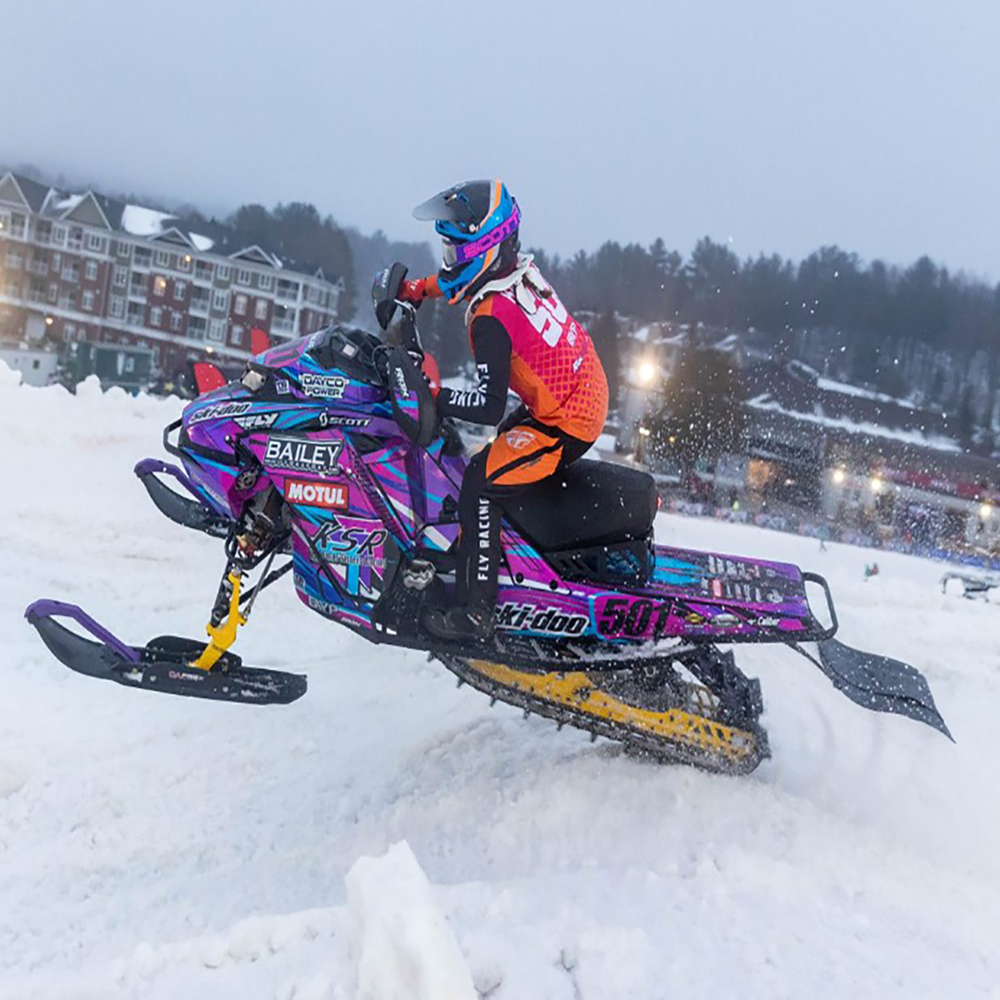 One of the Karkoulas sisters, Dakota, riding a snowmobile on black C&A Pro skis with purple handles. 